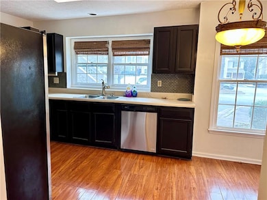 Kitchen with freestanding refrigerator, a sink, light wood finished floors, and stainless steel dishwasher