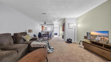 Living room with carpet, a textured ceiling, and baseboards