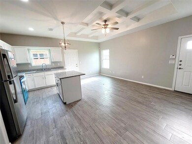 Kitchen with freestanding refrigerator, coffered ceiling, a kitchen island, white cabinetry, and recessed lighting