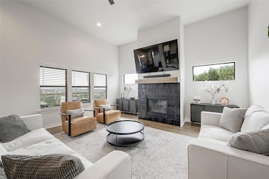 Living area with a high ceiling, a fireplace, lig