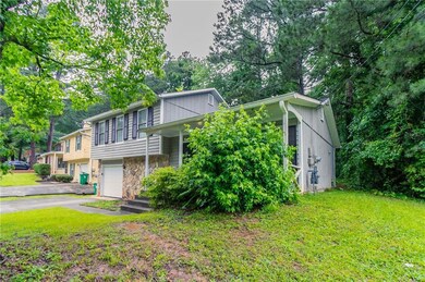 View of front of house with driveway, a garage, stone siding, and a front yard