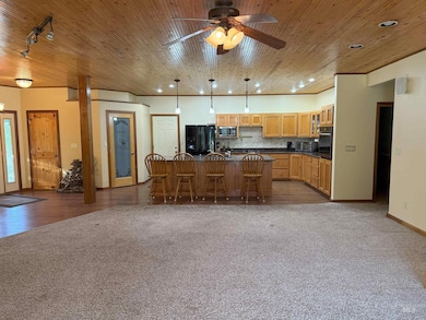 Kitchen featuring dark countertops, a kitchen breakfast bar, a kitchen island, dark carpet, and decorative backsplash