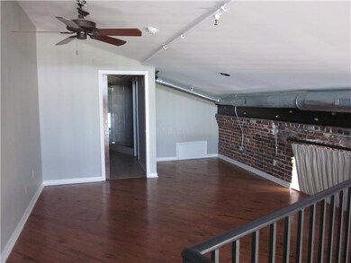 Lofted bedroom upstairs has hardwood flooring a fu