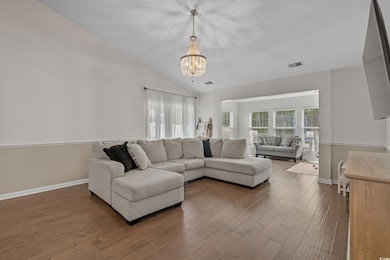 Living room featuring a chandelier, wood finished floors, and vaulted ceiling