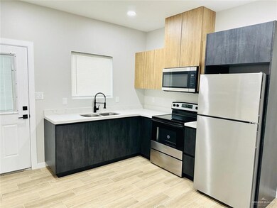 Kitchen featuring light countertops, modern cabinets, wood tiled floor, appliances with stainless steel finishes, and a sink