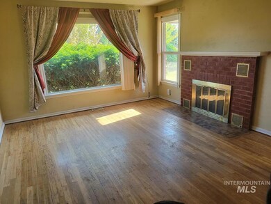 Unfurnished living room featuring wood-type flooring and a brick fireplace