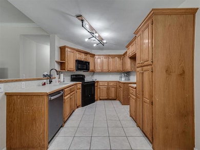 Kitchen with light countertops, brown cabinetry, light tile patterned flooring, and black appliances