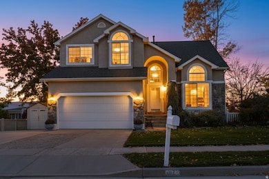 Traditional home with stucco siding, concrete driveway, stone siding, and a garage