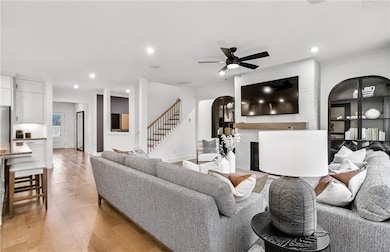 Living room with recessed lighting, stairway, a large fireplace, light wood-type flooring, and ceiling fan