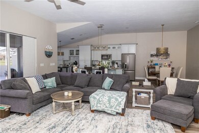 Living room with vaulted ceiling, ceiling fan, and