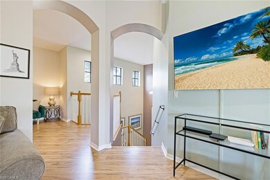 Hall with an upstairs landing, wood finished floors, and arched walkways