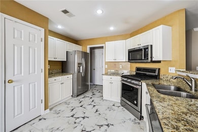 Kitchen featuring appliances with stainless steel finishes, light stone countertops, recessed lighting, and white cabinets