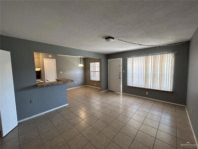 Unfurnished living room featuring a textured ceiling, tile patterned flooring, and baseboards