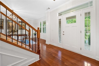 Entryway with wood finished floors, ornamental molding, stairs, a chandelier, and baseboards