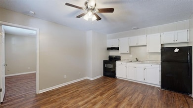 Kitchen featuring black appliances, dark wood-style floors, ceiling fan, white cabinets, and a textured ceiling