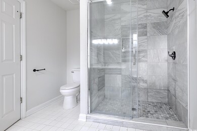 Bathroom featuring a shower with door, tile patterned floors, and toilet