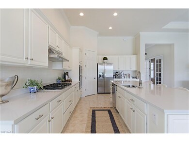 Spacious open concept kitchen with beautiful white cabinetry, quartz countertop, stainless upgraded appliances, center island with bar stools, range hood venting, and crown molding throughout.