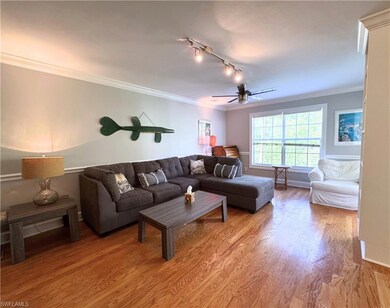 Living room featuring ceiling fan, light wood-type flooring, track lighting, ornamental molding, and baseboards