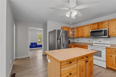 Kitchen featuring appliances with stainless steel finishes, a center island, ceiling fan, and light hardwood / wood-style floors