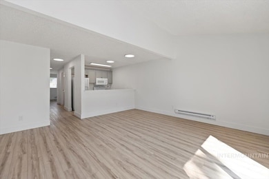 Unfurnished living room featuring light wood-type flooring, a textured ceiling, and baseboard heating