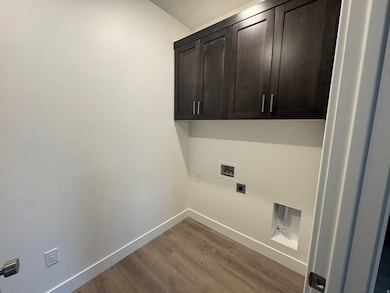 Laundry area with wood finished floors, cabinet space, hookup for a washing machine, and electric dryer hookup