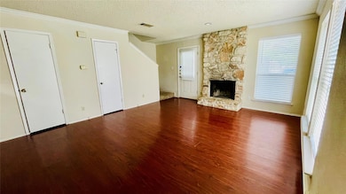 Unfurnished living room with ornamental molding, a textured ceiling, dark wood-style floors, and a fireplace