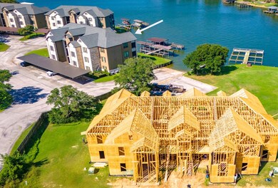 This photo shows a lakeside community with modern apartments and a new construction project in the foreground. The area features waterfront access and boat docks, offering scenic views and recreational opportunities.