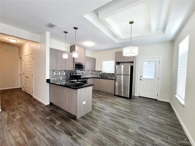 Kitchen with dark countertops, a raised ceiling, visible vents, appliances with stainless steel finishes, and a peninsula