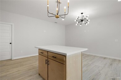 Kitchen with a chandelier, light wood-style floors, a center island, light countertops, and recessed lighting
