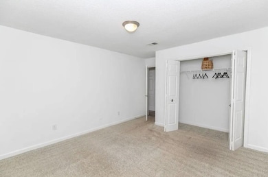 Unfurnished bedroom with light colored carpet, a c