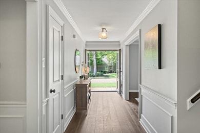 Doorway to outside featuring dark wood-style floors and crown molding