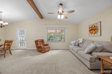 Carpeted living area featuring ceiling fan and a chandelier