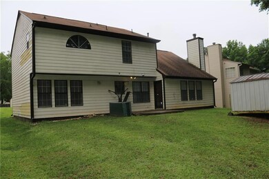 Rear view of house with a lawn, a chimney, and a storage shed