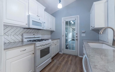 Kitchen featuring white appliances, lofted ceilin