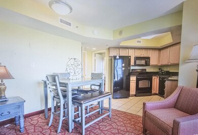 Kitchen featuring dark countertops, black appliances, light tile patterned flooring, and light brown cabinetry