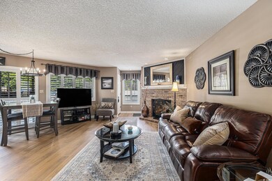 Living room featuring wood finished floors, a chandelier, a textured ceiling, and a fireplace