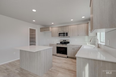 Kitchen with appliances with stainless steel finishes, light brown cabinetry, light wood-style floors, recessed lighting, and light countertops