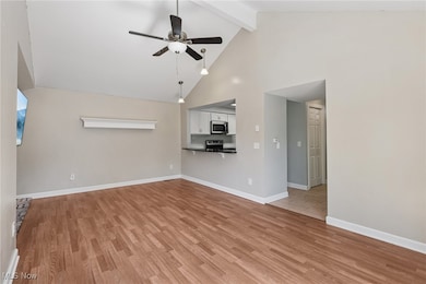 Unfurnished living room featuring light wood-type flooring, a ceiling fan, high vaulted ceiling, and beamed ceiling
