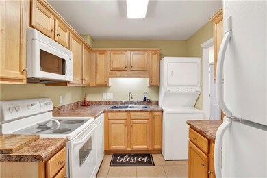 Kitchen with white appliances, stacked washer / dr