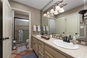 Full bath with double vanity, a shower stall, toilet, and a sink