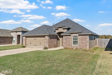 French country style house featuring a shingled roof, concrete driveway, brick siding, and a garage