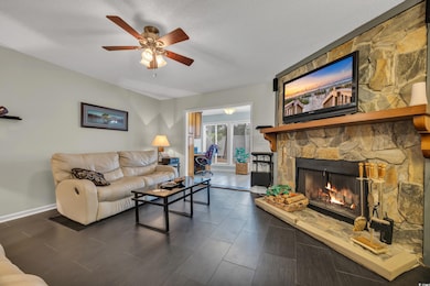 Living area with a ceiling fan, a fireplace, and baseboards