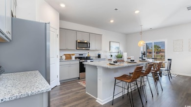 Virtually staged Kitchen with appliances with stainless steel finishes, gray cabinetry, dark wood-style floors, and recessed lighting