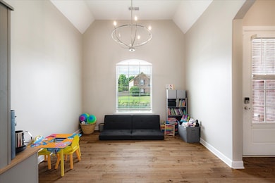 Playroom featuring a chandelier, wood finished floors, vaulted ceiling, arched walkways, and baseboards