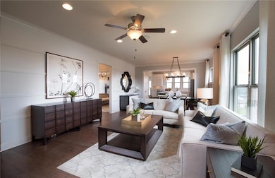 Living room featuring ornamental molding, wood finished floors, a chandelier, a ceiling fan, and recessed lighting