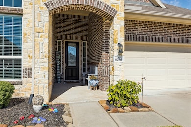 This entryway presents an elegant combination of brick and stone, complemented by a covered front porch. The entrance door includes decorative glass accents, creating a refined and inviting introduction to the home.