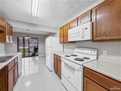 Kitchen featuring white appliances, light tile patterned flooring, decorative light fixtures, and sink