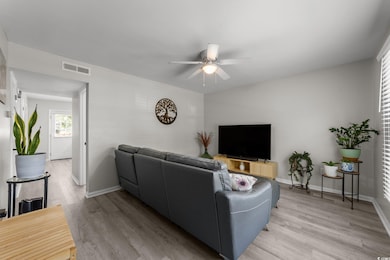 Living room with light wood-style floors, a ceiling fan, and baseboards