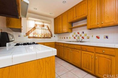 clean kitchen with wooden cabinets & tile counter 
