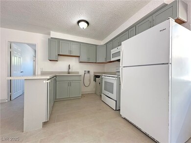 Kitchen with white appliances, a sink, a textured
